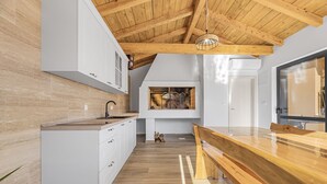 Een moderne keuken met witte kastjes, een houten aanrecht en een houten plafond.