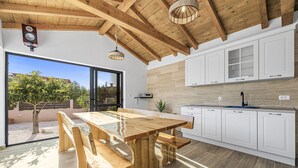 Een moderne keuken met houten balken, witte kasten en een grote eettafel met banken.