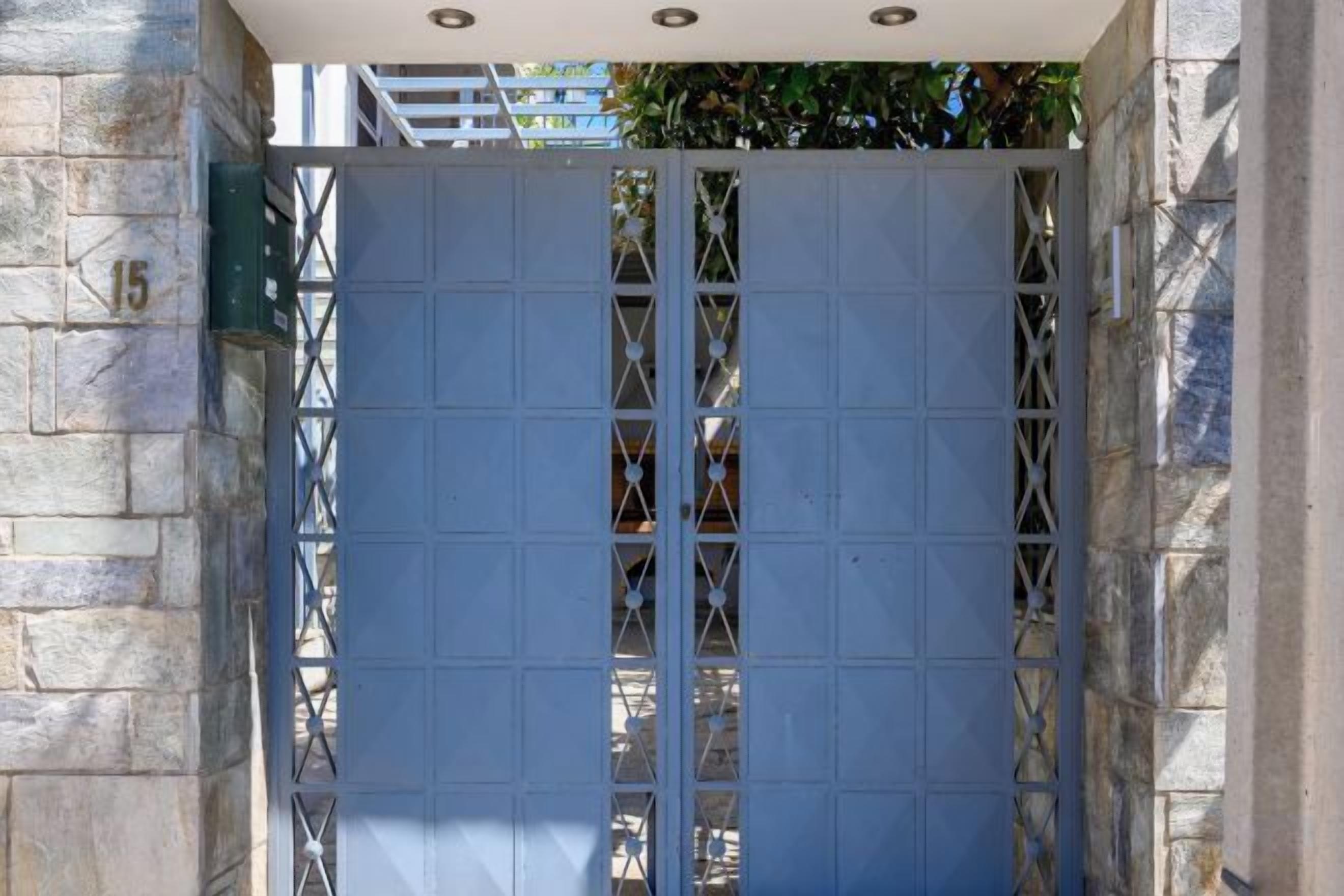 A metal gate with a grid pattern, set within a stone wall.