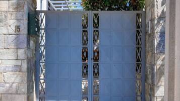A metal gate with a grid pattern, set within a stone wall.