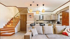 Una sala de estar moderna con una escalera, un sofá y una zona de cocina.