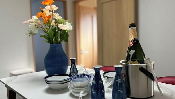 Une table ornée d’un vase de fleurs, d’une bouteille de champagne et de divers verres.