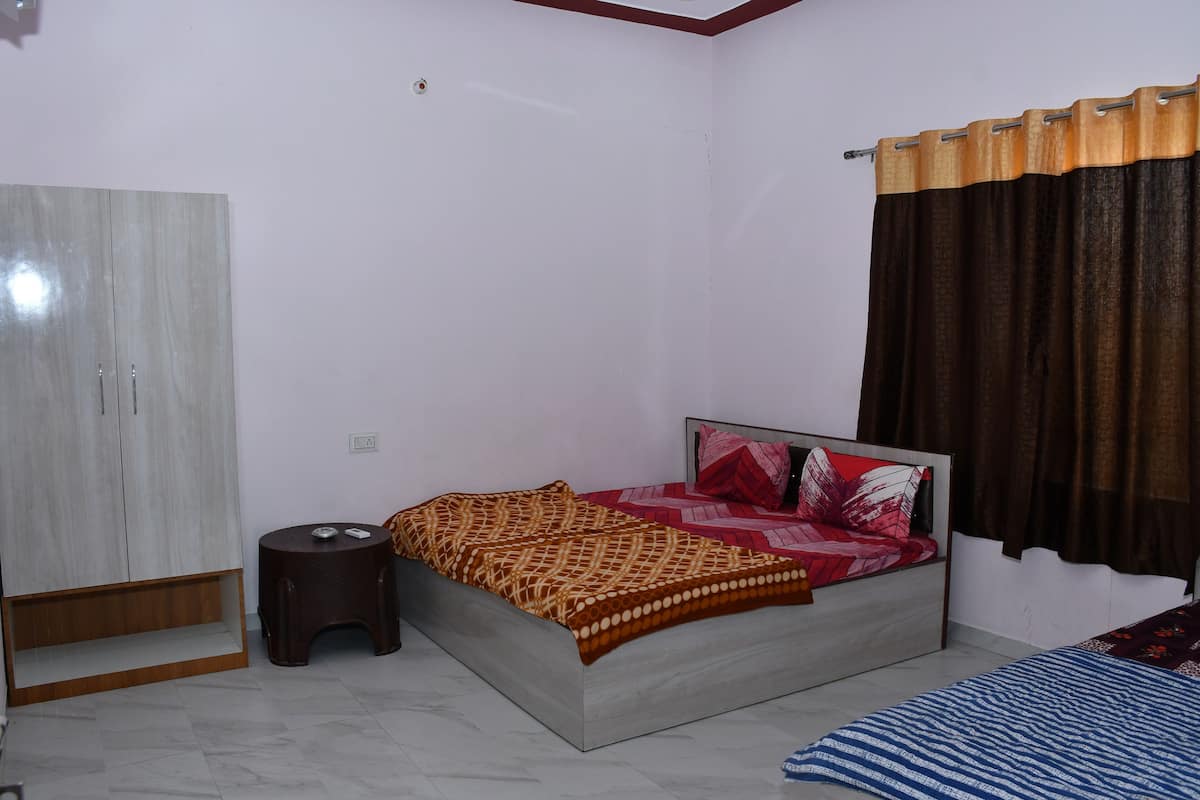 Une chambre à coucher avec un lit, une armoire, un petit tabouret et un rideau.