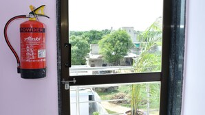 Un extintor de incendios sujeto a la pared junto a una puerta, con vistas a un balcón y una planta en maceta.