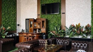 A lounge area with leather sofas, a bar, and a television mounted on a green wall. - Marco Polo (Tashkent)