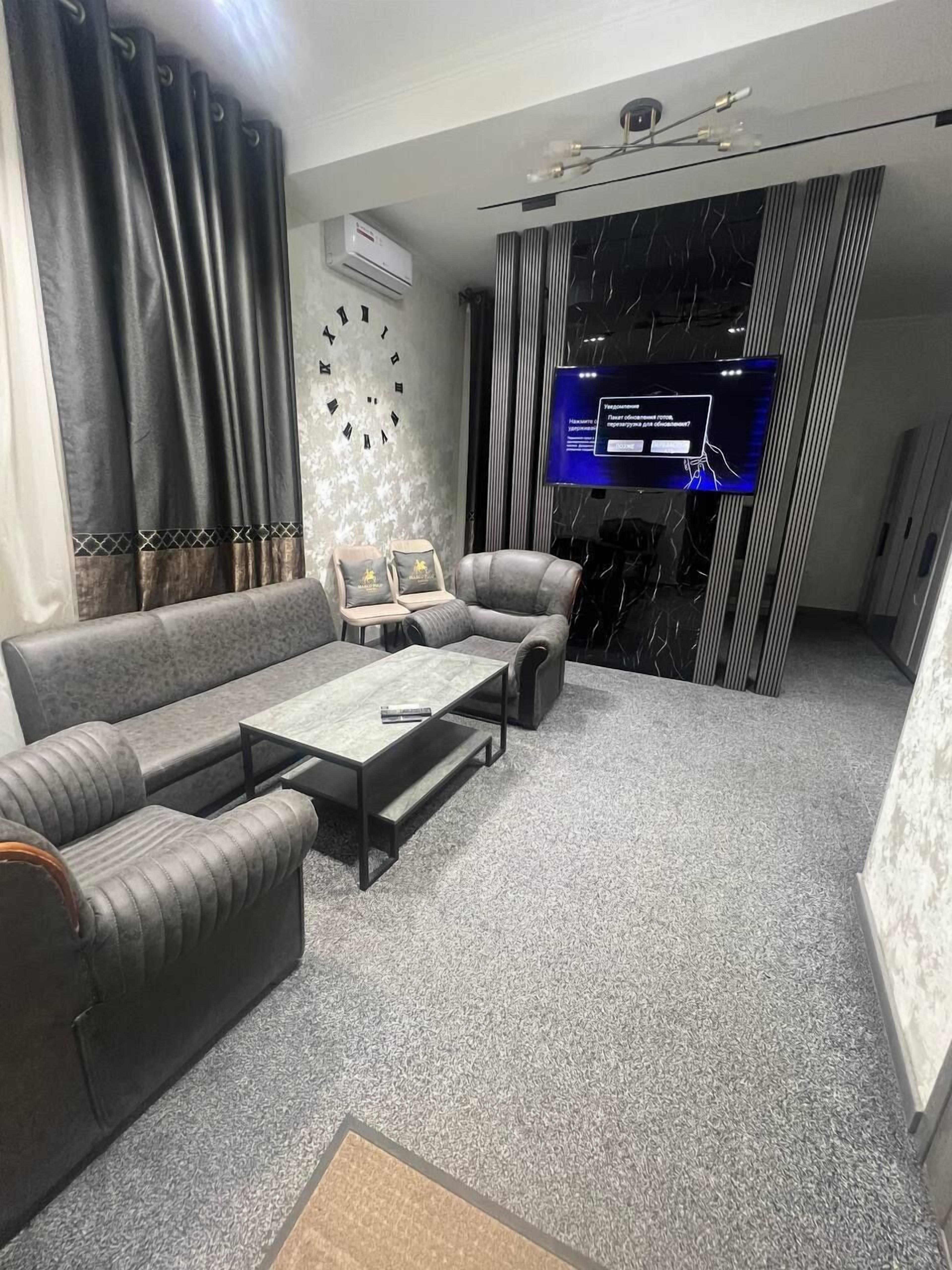 Uma sala de estar moderna com um sofá, poltronas, uma mesa de centro e uma televisão.