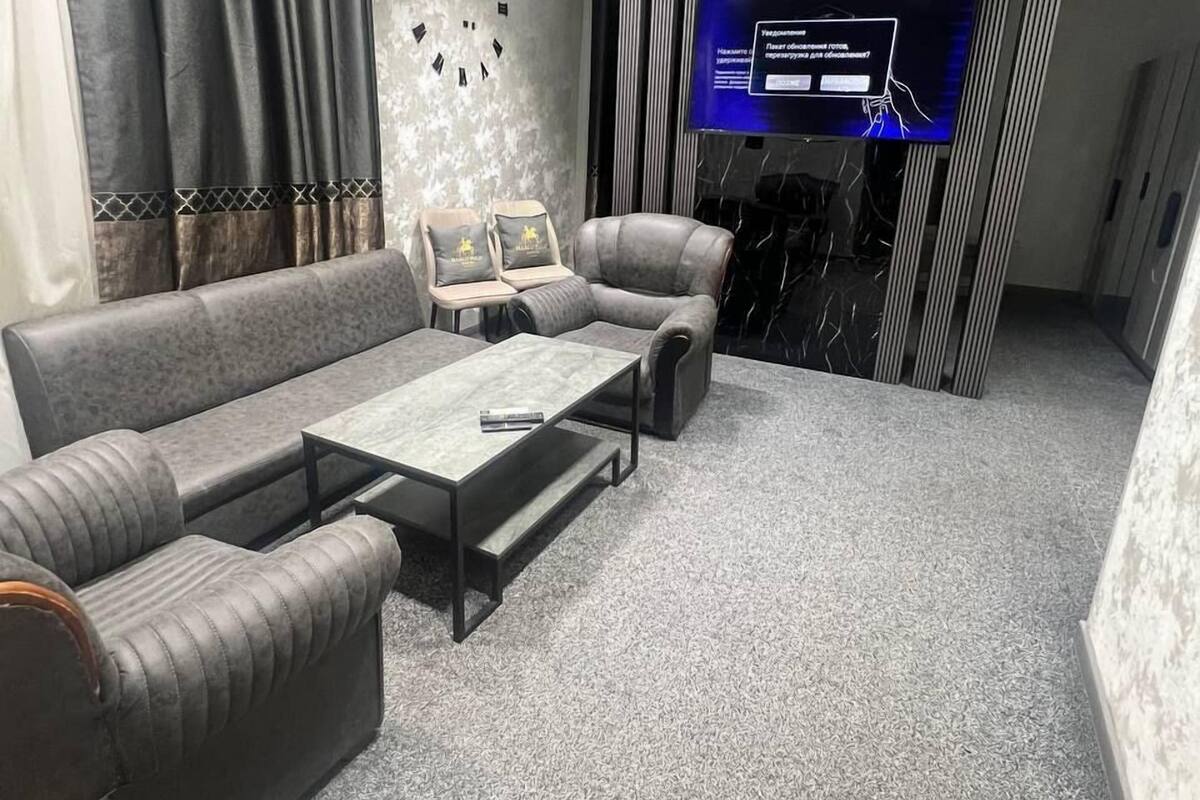 A modern living room with a sofa, armchairs, a coffee table, and a TV.