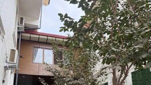 A modern house with a living room, a dining area, and a small garden with artificial grass and a tree. - Marco Polo (Tashkent)