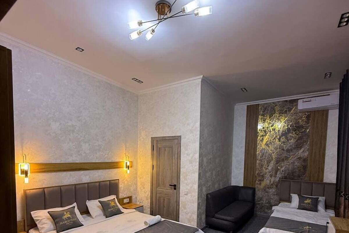 A hotel room with a large bed, a desk, a chair, and a stone wall feature.