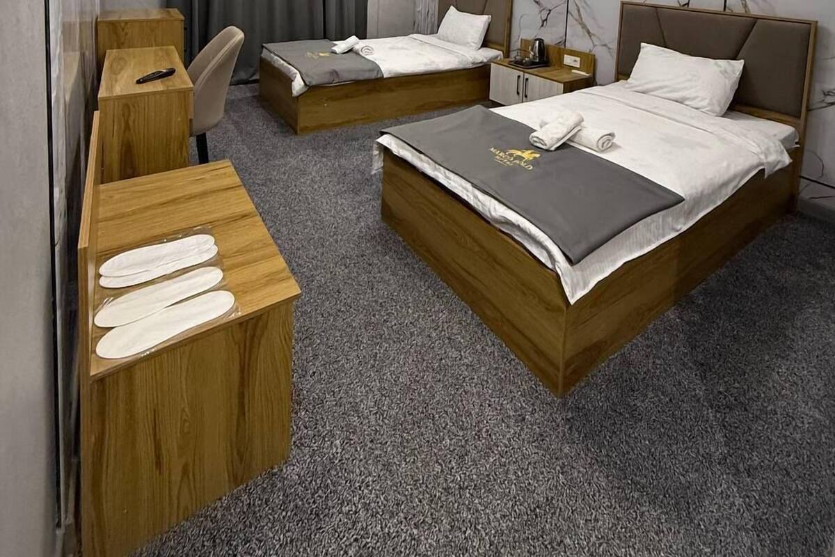 A hotel room with two beds, a desk, a chair, a wardrobe, and a marble-patterned wall.