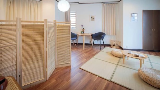 A room with tatami flooring, a low table with a cushion, a chair, and a wooden partition. - Skyview Serenity Duplex Shinjuku (Tokyo)