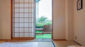 A room with tatami flooring, a sliding shoji screen, a bed, and a view of a garden. - Skyview Serenity Duplex Shinjuku (Tokyo)