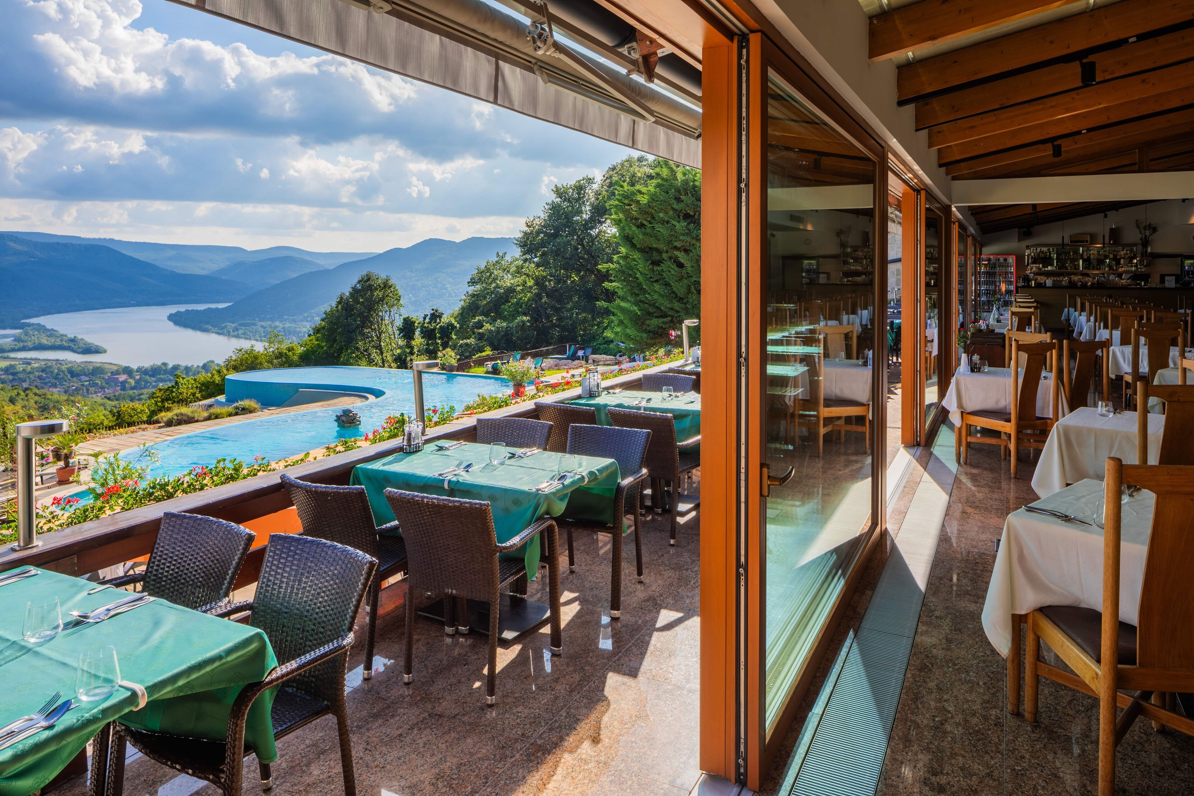 Ein Restaurant mit Außenbereich, das auf einen See und die Berge blickt.
