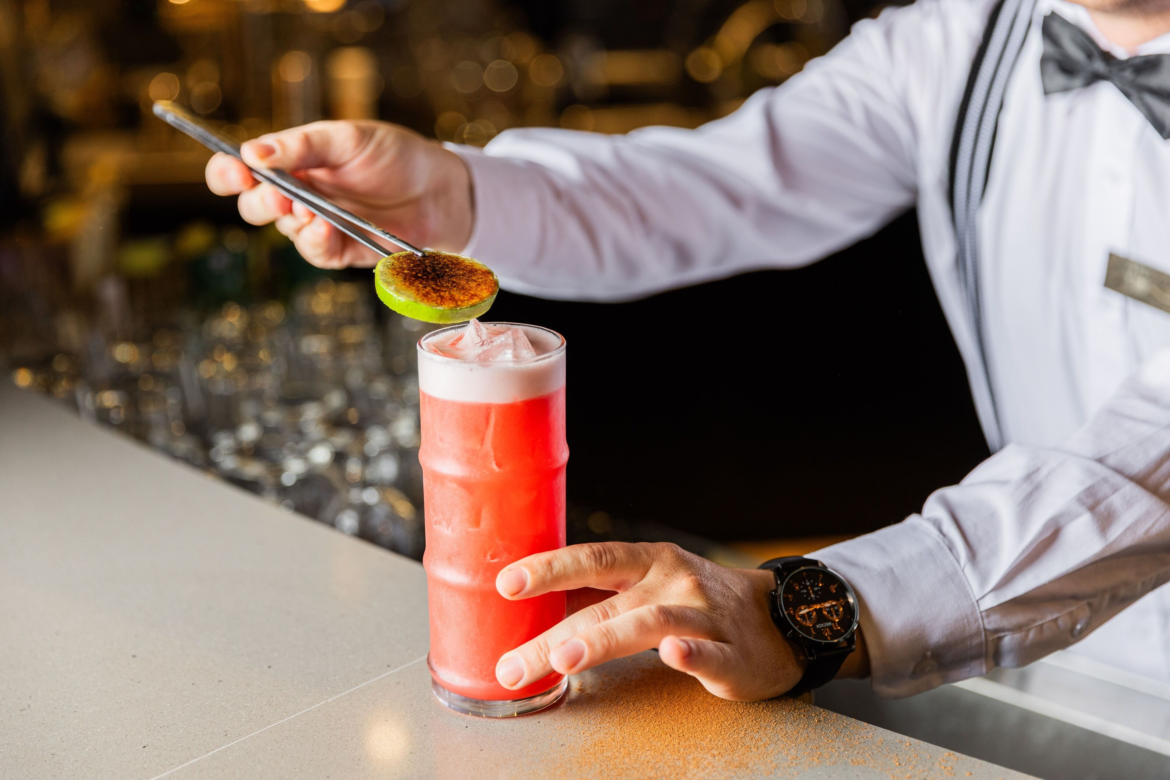 Een bartender bereidt een cocktail met een limoen.