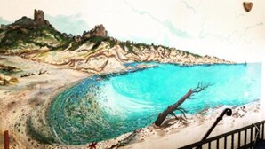 A mural of a coastal scene with a wave, a tree, and rocky terrain. - Villa Le Torri Porto Corallo (Villaputzu)