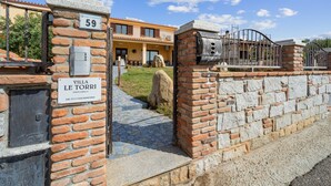Villa Le Torri with a stone wall entrance, a metal gate, and a clear blue sky. - Villa Le Torri Porto Corallo (Villaputzu)