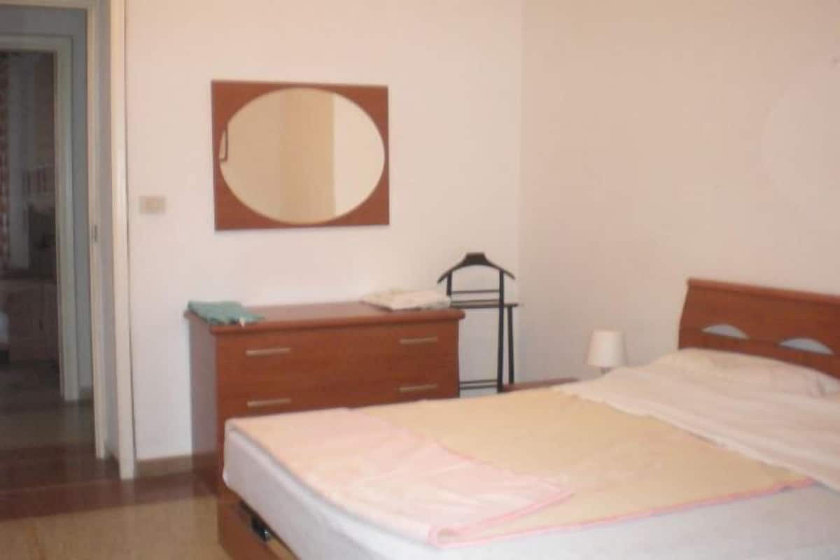 Une chambre à coucher avec un lit, une commode, un miroir et une table de chevet.