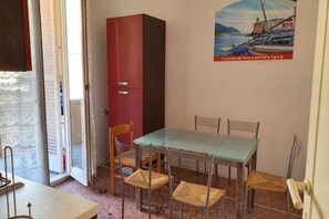 Un coin repas avec une table et des chaises, un buffet rouge et une porte donnant sur une autre pièce.