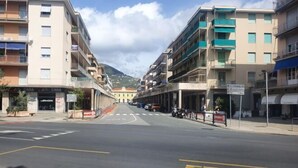 Une rue avec une voie réservée aux autobus, des immeubles dotés de balcons et une montagne en arrière-plan.