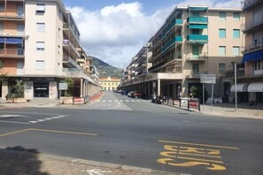 Une rue avec une voie réservée aux autobus, des immeubles dotés de balcons et une montagne en arrière-plan.