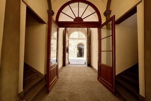 Un couloir avec un cadre de porte en bois, un sol en pierre et une vue sur une autre pièce.