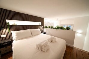 A bedroom with a bed, bedside tables, a window with plants, and a wall-mounted shelf. - Bella Benci Firenze Apartment (Florence)
