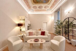 A living room with a white sofa, two armchairs, a coffee table, a lamp, and a decorative ceiling. - Bella Benci Firenze Apartment (Florence)