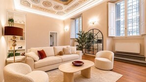 Un salon comprenant un canapé, deux fauteuils, une table basse, un lampadaire et une plante.