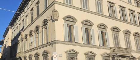 A multi-story building with a classical architectural style, featuring arched windows and a balcony.