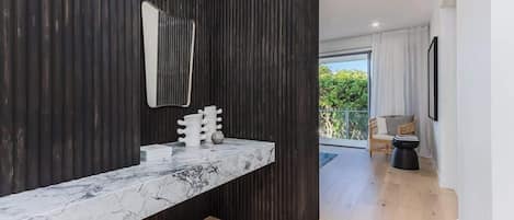 Un bagno moderno con un piano in marmo, uno specchio grande e una parete nera.