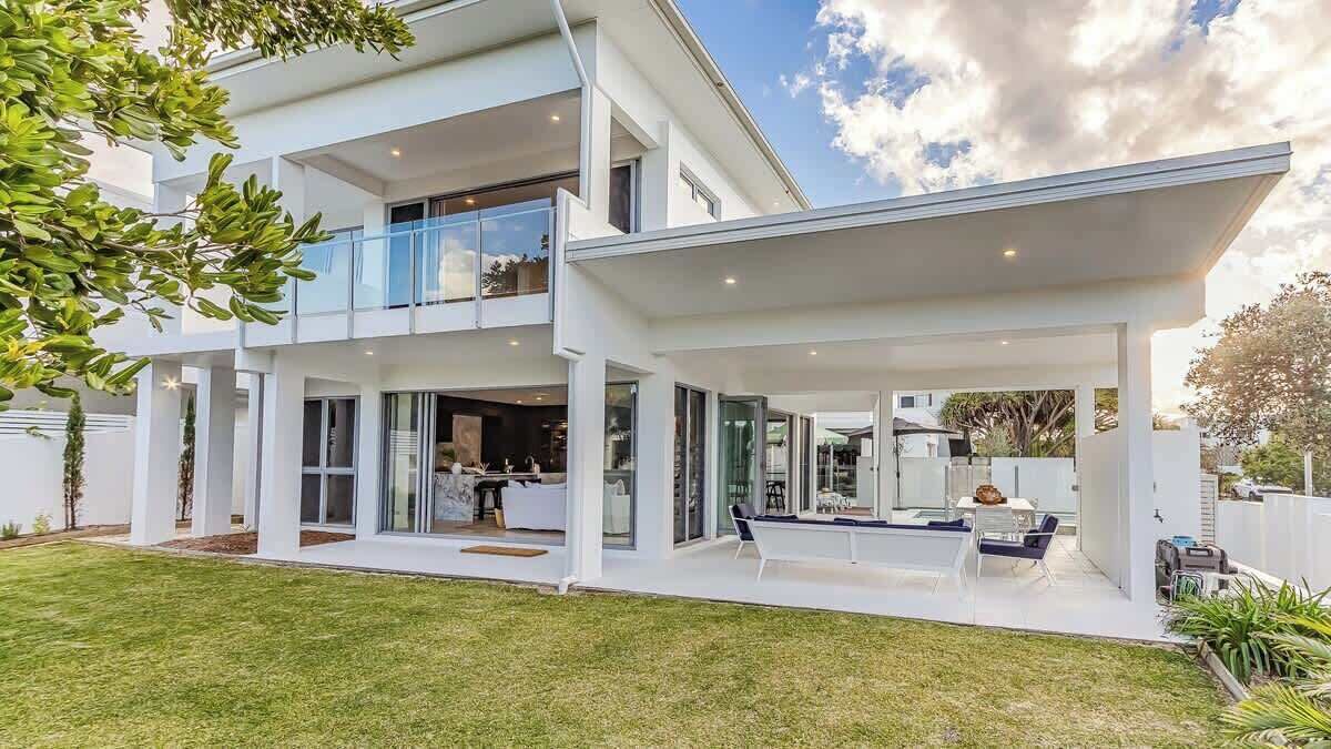 A modern two-story house with a covered patio, a dining area, and a visible kitchen.