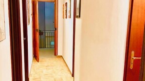 A hallway with wooden flooring, a red door on the right, and a view into a balcony area. - House Scala Dei Turchi (Realmonte)