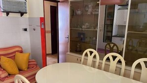 A dining area with a round table and chairs, a striped sofa with yellow cushions, and a glass-fronted cabinet with shelves. - House Scala Dei Turchi (Realmonte)