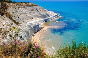 Un paisaje costero con formaciones rocosas blancas en capas y una playa arenosa.