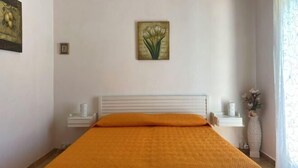 A bedroom with a bed, a nightstand, a vase with flowers, and a painting on the wall. - House Scala Dei Turchi (Realmonte)