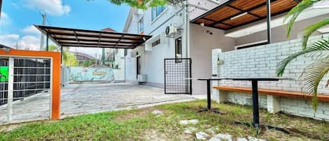 A courtyard with a covered seating area, a gate, and a bench.