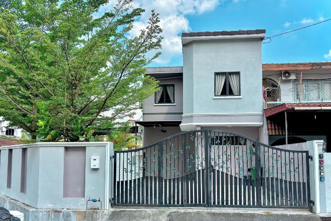 A modern two-story house with a gated entrance, a small balcony, and a tree in the foreground.
