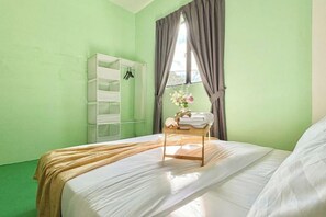 Un dormitorio con cama, una mesita de noche con lámpara, una ventana con cortinas y un armario.
