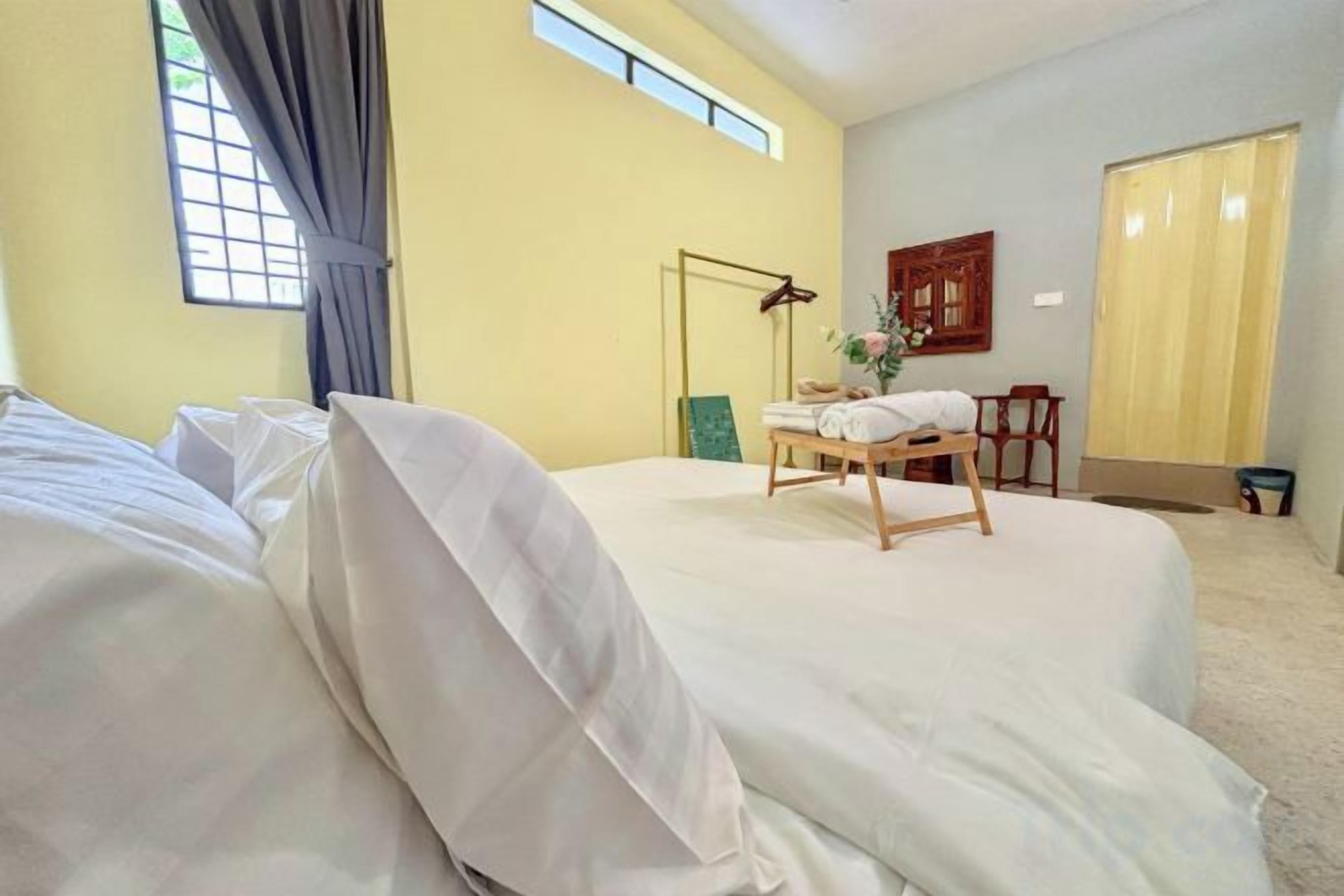 Ein Hotelzimmer mit Bett, Schreibtisch, Stuhl, Lampe und einem fenster mit Vorhängen.