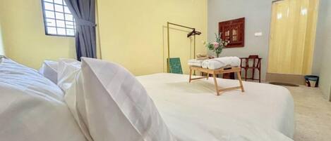 Ein Hotelzimmer mit Bett, Schreibtisch, Stuhl, Lampe und einem fenster mit Vorhängen.
