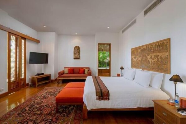 A bedroom with a large bed, a TV, a sofa, a window, and a painting on the wall. - Villa Praison (Phuket)