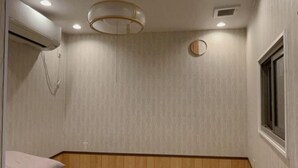 Une pièce avec un plancher en bois, un lit avec des oreillers, un élément de décoration circulaire au mur et une fenêtre.