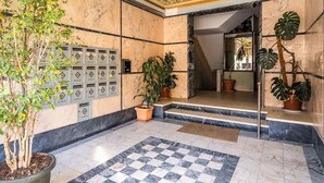 A lobby with marble flooring, potted plants, a checkered rug, and a staircase leading to another area. - Jambul Apartment, Graça, Lisbon (Lisboa)