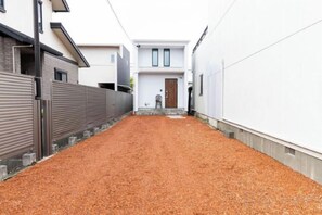 A narrow alleyway with a gravel path leading to a building with a wooden door and a small step. - 【Antiques Gifu Station East】Entire Villa for up to 10 Guests 10-Min Walk from JR Gifu Station (Gifu)