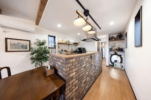 A modern kitchen with a brick island, wooden dining table, and pendant lighting.