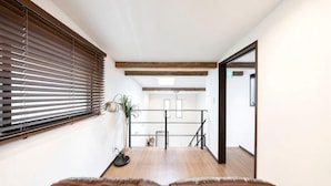 A room with a wooden floor, a bed with brown bedding, a window with blinds, and a plant. - 【Antiques Gifu Station East】Entire Villa for up to 10 Guests 10-Min Walk from JR Gifu Station (Gifu)