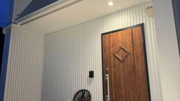 A building with a wooden door and a small black chair outside.