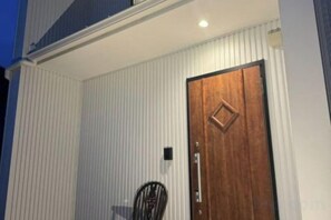 A building with a wooden door and a small black chair outside. - 【Antiques Gifu Station East】Entire Villa for up to 10 Guests 10-Min Walk from JR Gifu Station (Gifu)