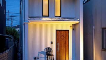 A modern two-story building with a wooden door and a chair outside.