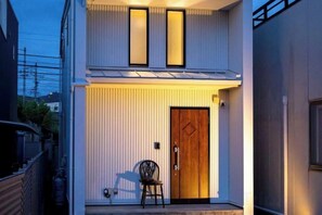 A modern two-story building with a wooden door and a chair outside. - 【Antiques Gifu Station East】Entire Villa for up to 10 Guests 10-Min Walk from JR Gifu Station (Gifu)